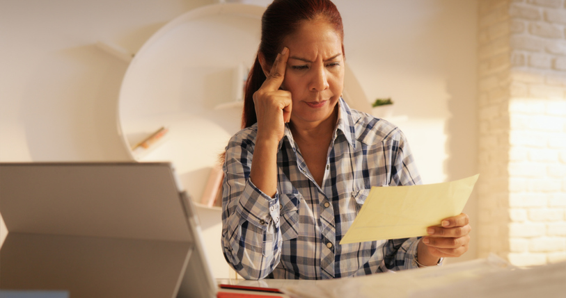 A woman reviewing a financial document at home