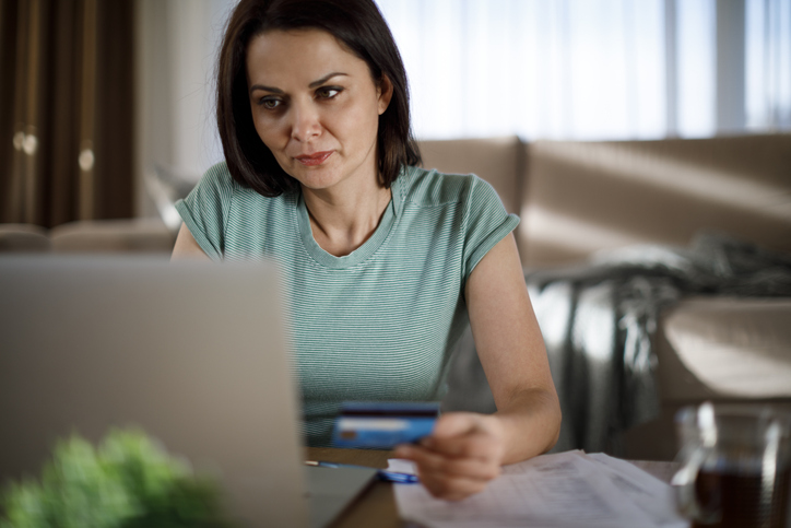 A woman reviews bills and financial documents on a laptop