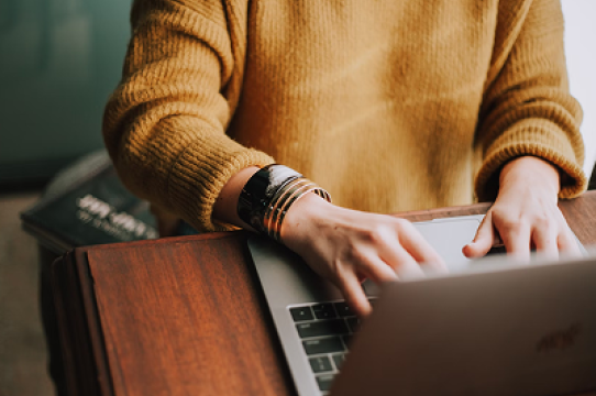 adult typing on laptop