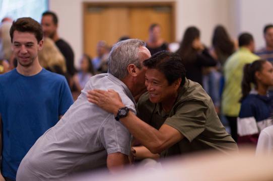 two men hugging in a crowded room