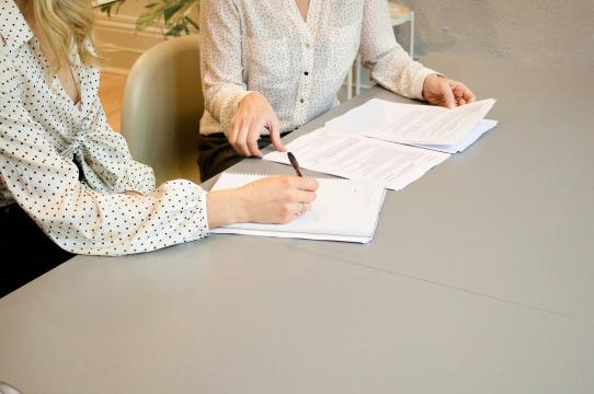 two women at a table signing papers