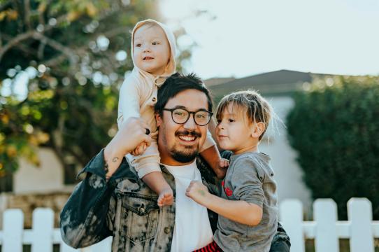 a man holding a child with baby on shoulders