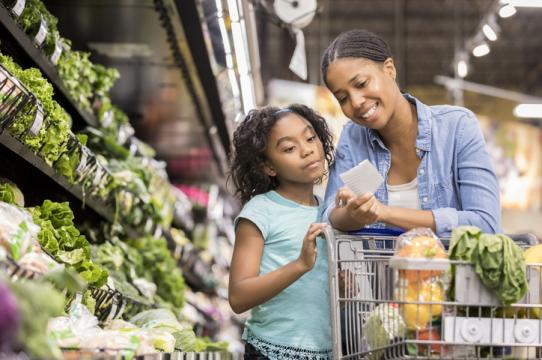 Mother and daughter shopping for fresh produce together at a grocery store