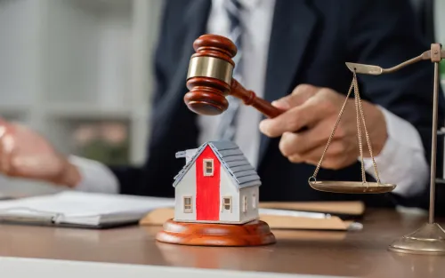 A judge strikes a gavel beside a small house model, symbolizing property law, housing disputes, or real estate judgment