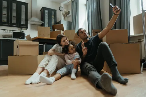 A family sits together among moving boxes in their new home, celebrating a fresh start.