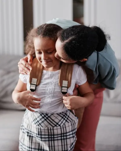 Parent embracing a child wearing a school backpack