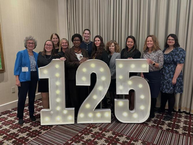 GBLS team standing in front of large lighted numbers 125